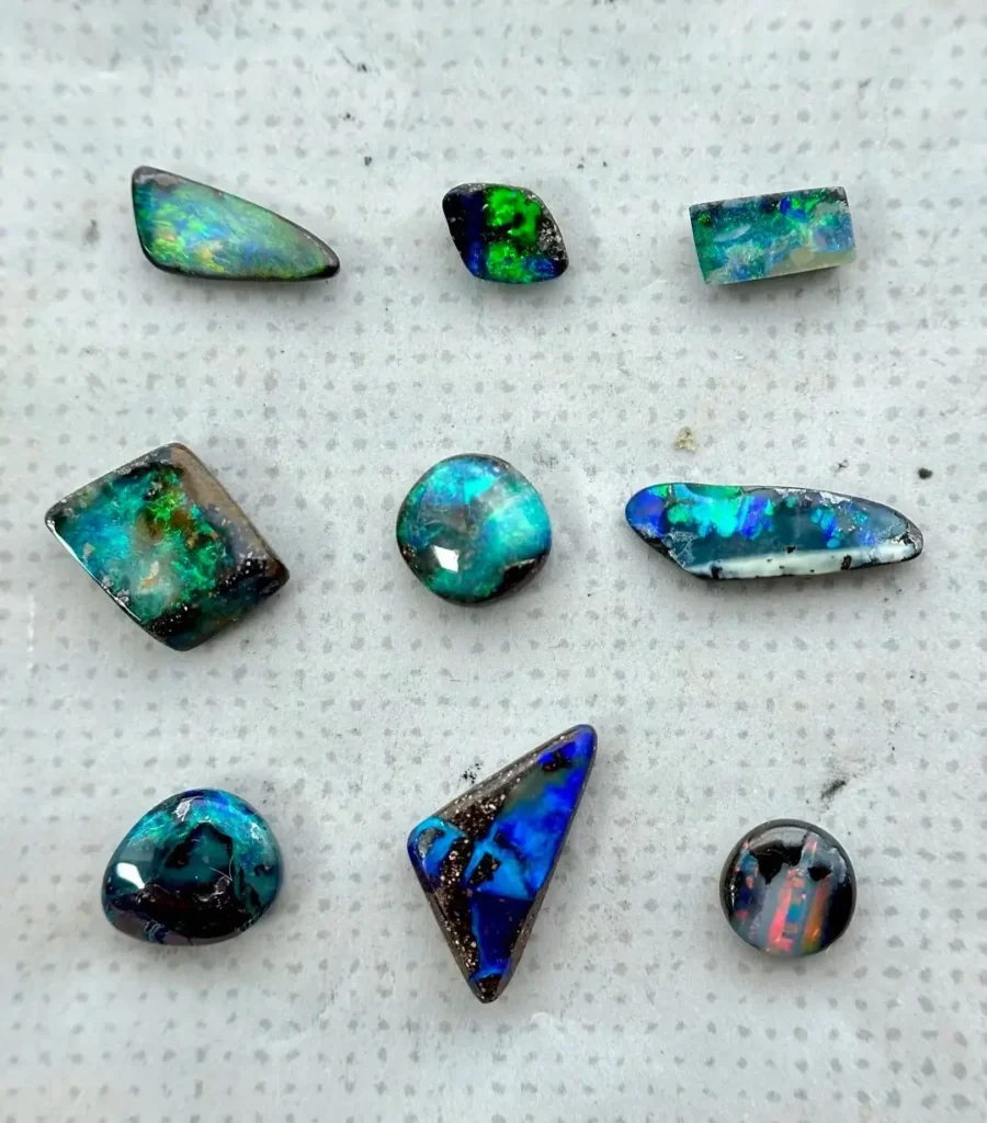 A set of Australian boulder opals in natural light showing opal layers on dark ironstone rock.