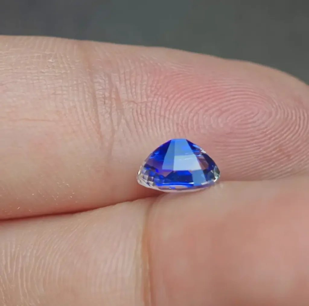 Side profile of an Ottu sapphire showing a vivid blue tip and a mostly colorless crystal body.
