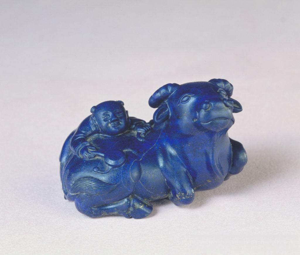 A Qing Dynasty lapis lazuli carving of a boy riding a water buffalo with golden pyrite flecks.