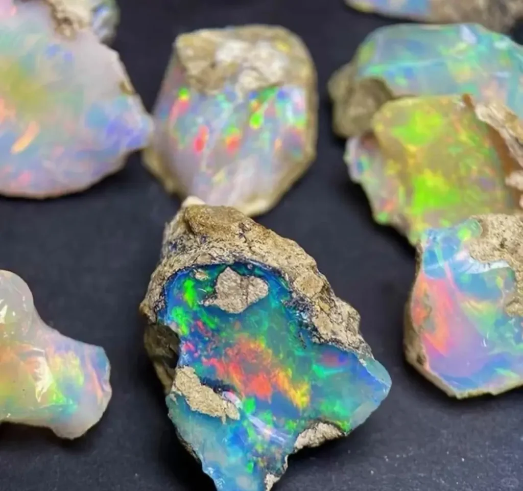 A group of rough Australia gemstones—unpolished opal specimens showing fiery play-of-color on rock.