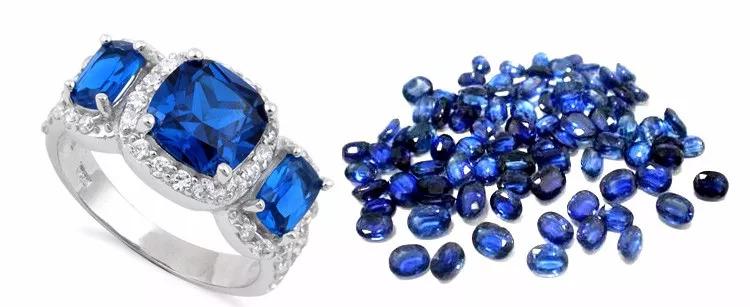 A sapphire gemstone ring displayed alongside a collection of loose faceted blue sapphires.
