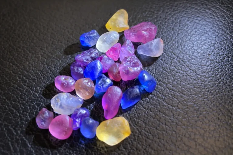 A collection of colorful Sri Lankan sapphires arranged on a textured leather gem mat.