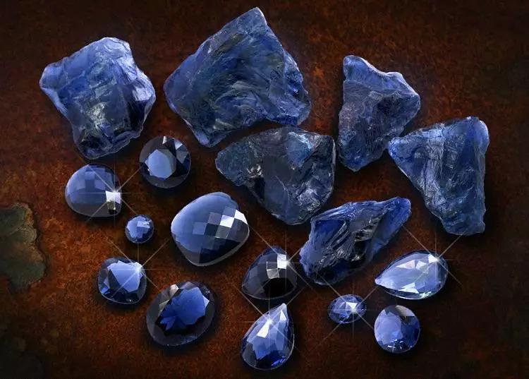 A collection of raw Tanzanite crystals paired with polished, faceted Tanzanite gemstones.