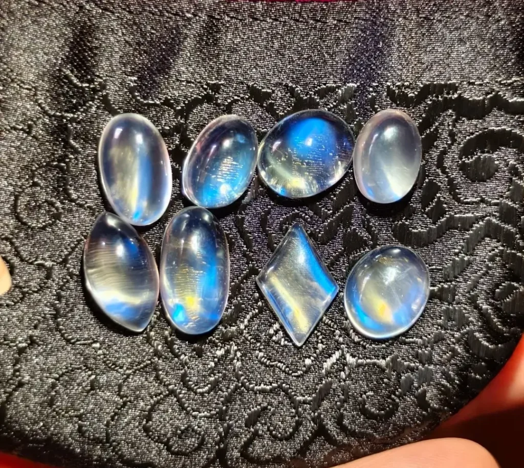 A group of transparent Sri Lankan moonstones exhibiting vivid blue sheen on colorless, glass-like crystals.