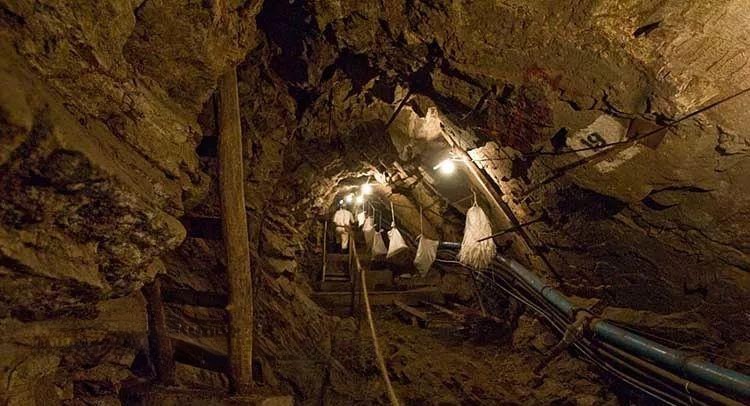 Miners transporting raw ore containers through a narrow underground tunnel in the Merelani mines.