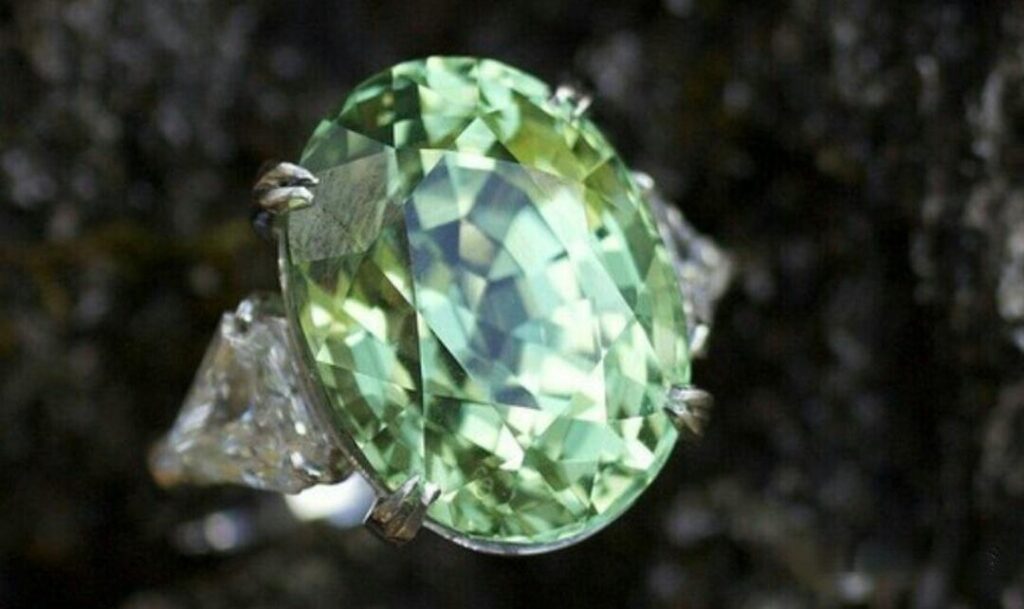 A faceted mint green vanadium chrysoberyl set in a classic four-prong gold ring.