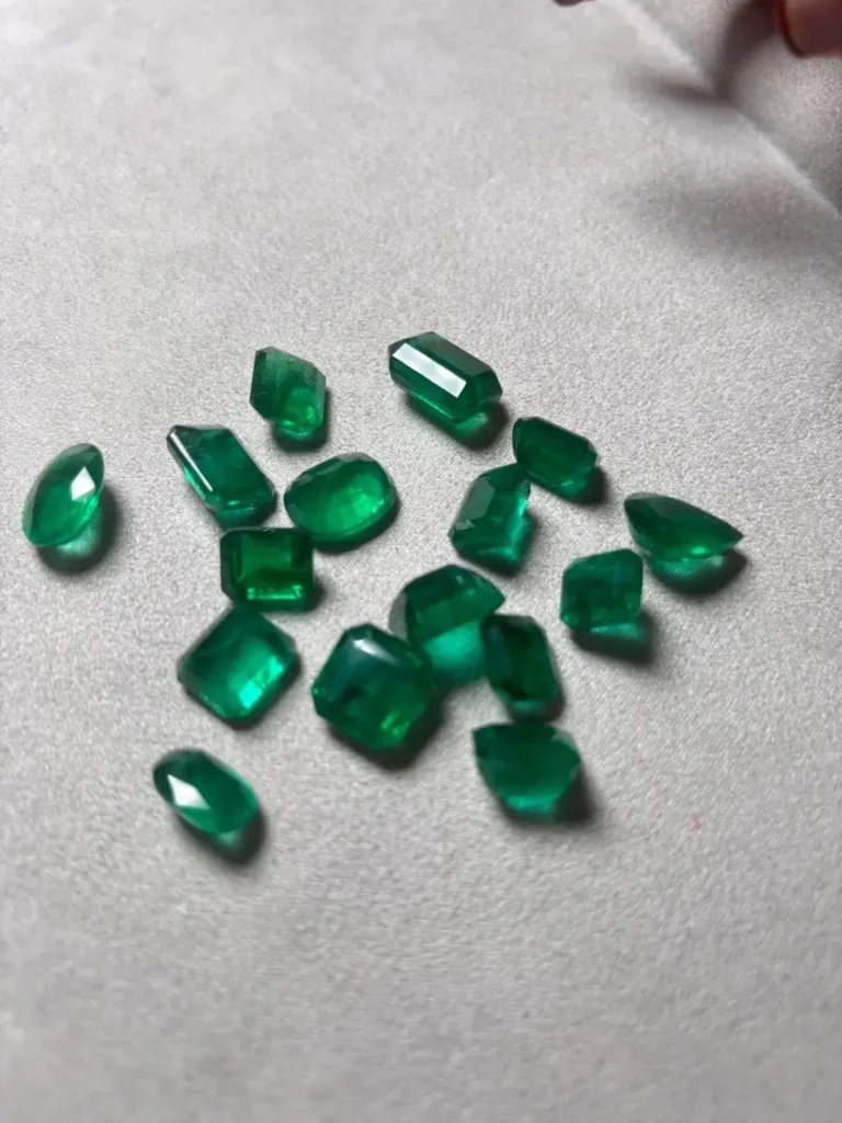 A group of vivid green emerald-cut gemstones displaying high clarity and deep saturation.