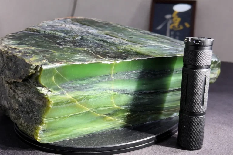 An 8.6kg raw jade with a 1cm pale-green interlayer compared to a gemological torch.