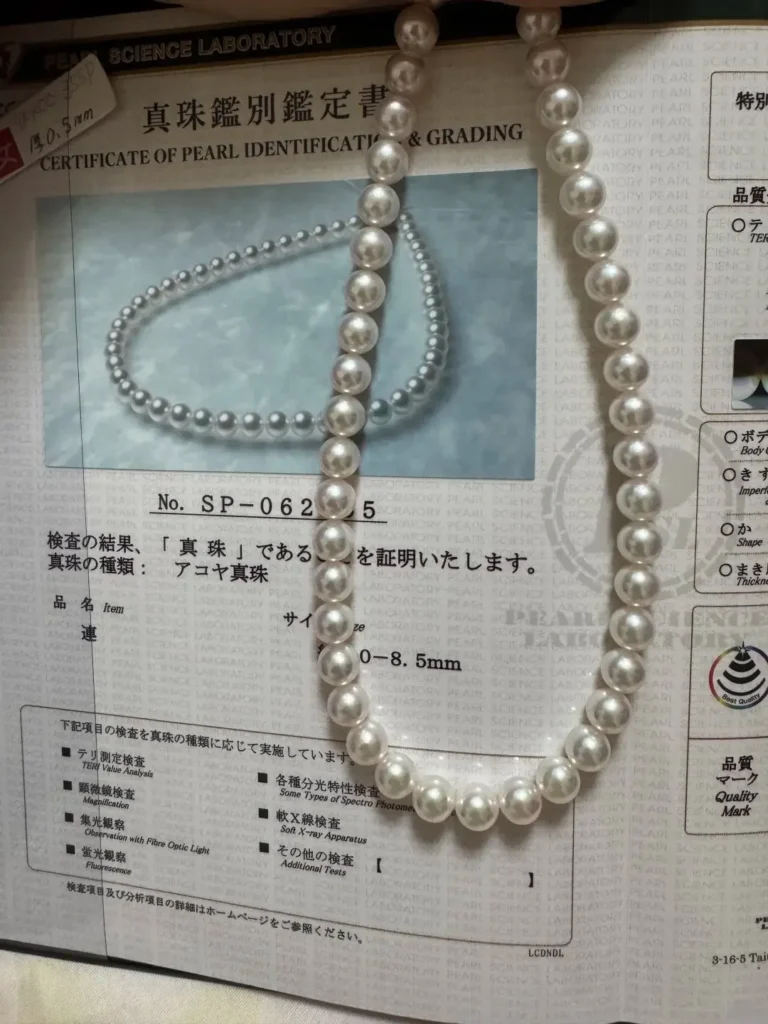 An 8-8.5mm Tennyo Akoya necklace with JPSL certificate showing pink and green interference colors.