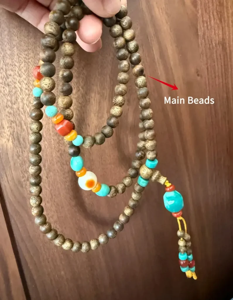 A 108-bead agarwood Mala with an arrow pointing to the primary Main Beads anatomy.