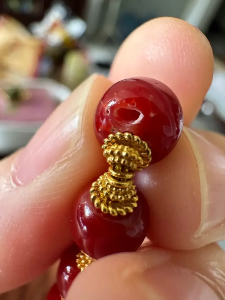 Close-up of Aka red coral beads showing tiny natural wormholes and a subtle white core.
