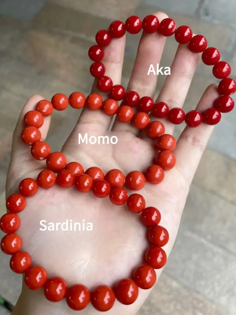 Comparison of Aka, Momo, and Sardinia red coral bead bracelets held in a palm.