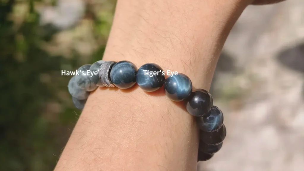 A wrist displaying a bracelet of mixed blue Tiger’s Eye and Hawk’s Eye beads.