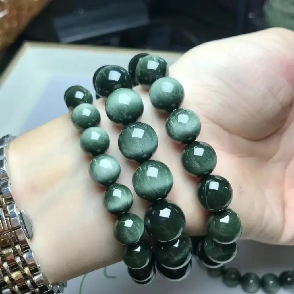 A wrist displaying a blue Hawk’s Eye bracelet with deep steel-blue and grayish tones.