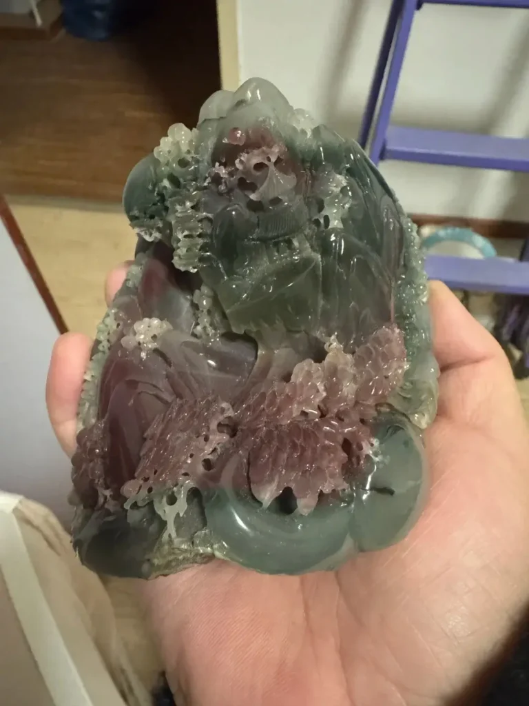 Handheld Purple-Green Agate carving showing distinct zones of saturated green and deep purple.