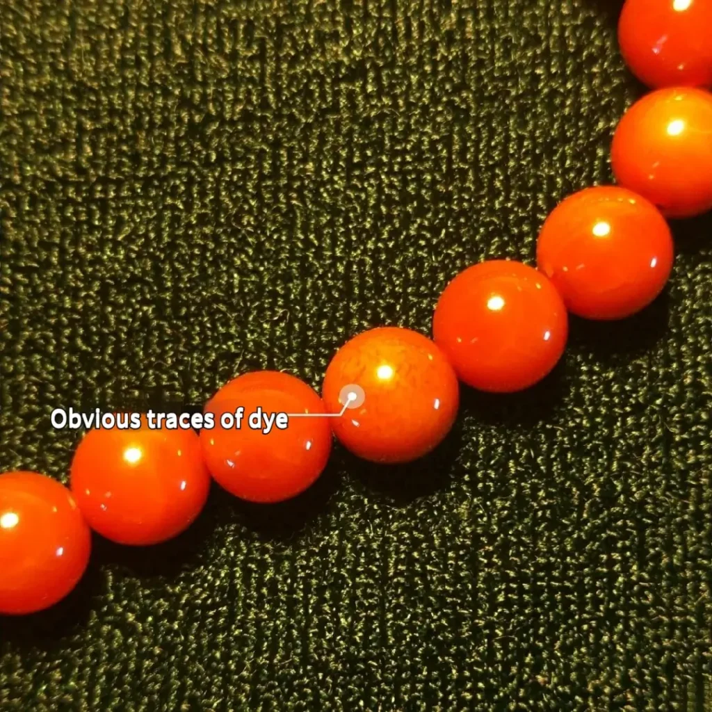 Dyed agate beads mimicking Nanhong, showing clear signs of artificial staining at the marked areas.