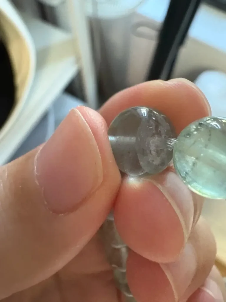 Close-up of Fluorite beads with white surface cracks and flat spots near the drill holes.