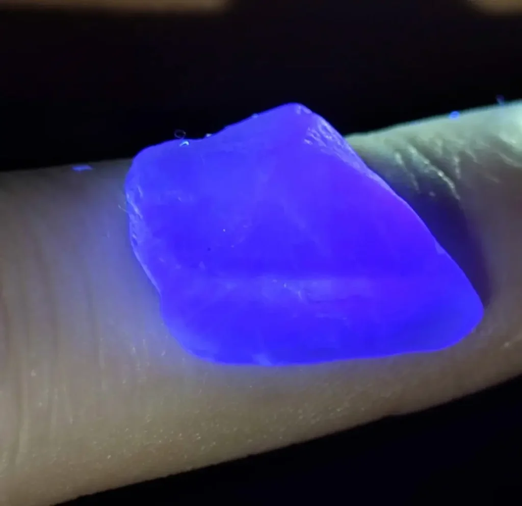 A green crystal shifting to a deep purple hue under focused artificial light.