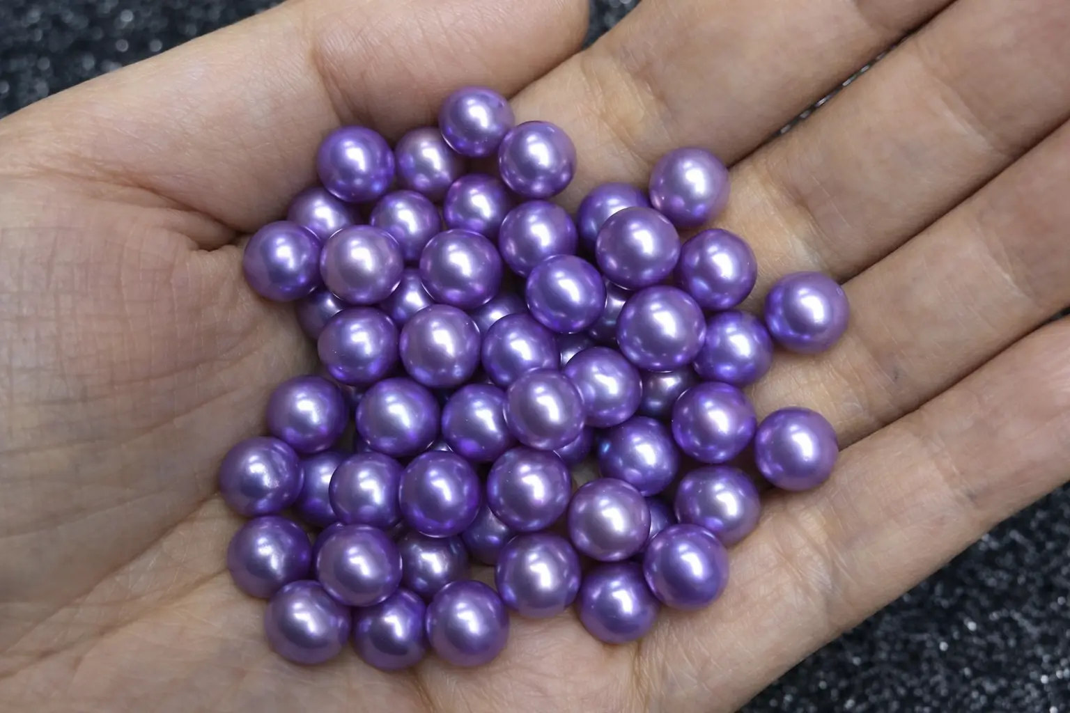 Handful of low-quality dyed purple pearls with dull and matte surface finish.