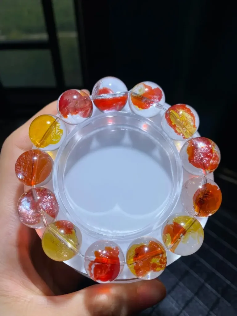 A Hematoid Quartz bracelet featuring vibrant, petal-like red and orange mineral inclusions suspended in clear quartz.