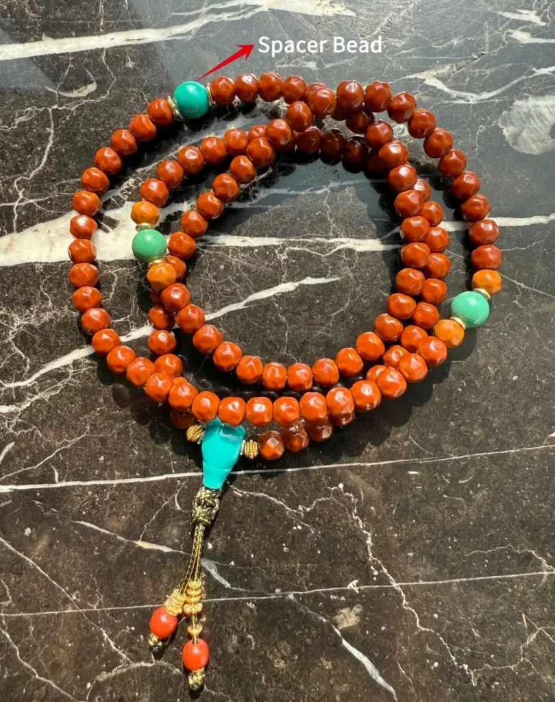 A 108-bead Mala with arrows pointing to the decorative spacer beads in its anatomy.