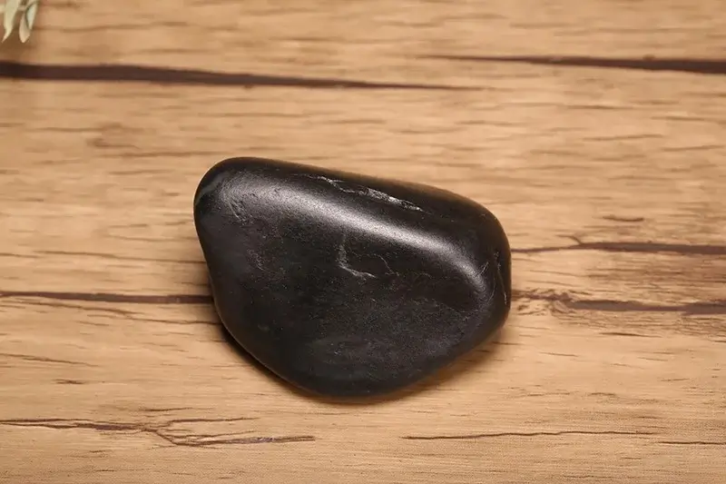 A Black Hetian Jade (Mo Yu) seed stone with a smooth, water-worn surface showing natural graphite coloration.