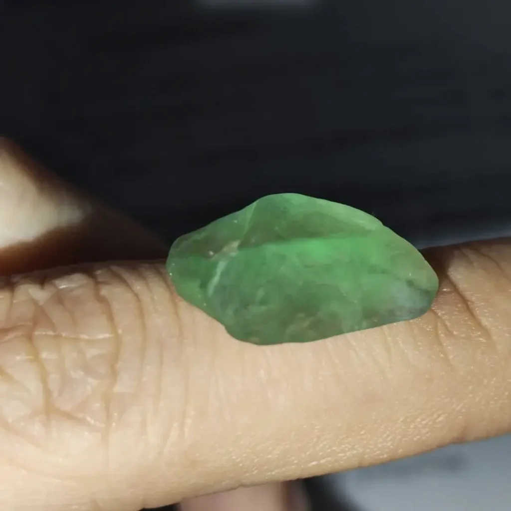 A raw green stone crystal cluster with cubic structures under natural ambient light.