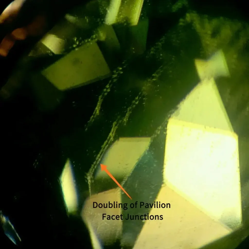 An arrow points to the distinct doubling of back facet junctions in a faceted green peridot.
