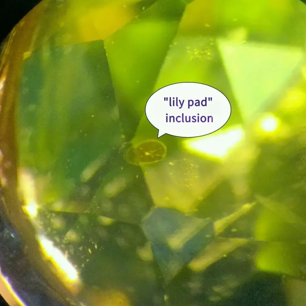 Microscopic view of a peridot lily pad inclusion with an arrow pointing to the stress halo.