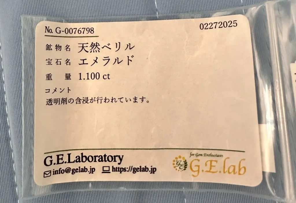 Vendor-issued certificate card stating "Natural Emerald" and listing carat weight.