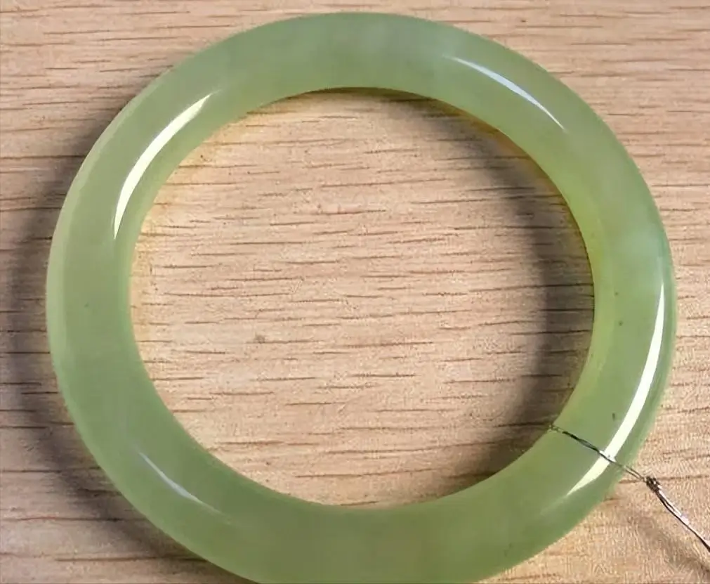 Highly translucent Xiuyan Serpentine jade bangle with a pale green to yellow water-like luster.