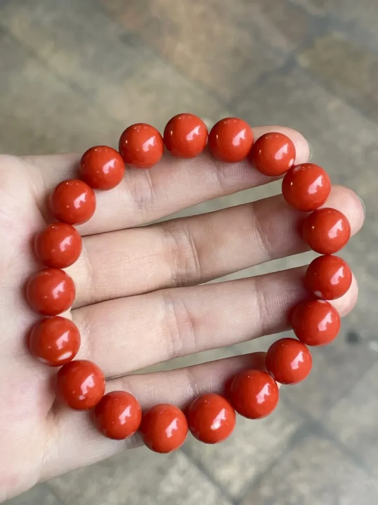 A vibrant red Momo coral bead bracelet showcasing a dense, porcelain-like matte finish.