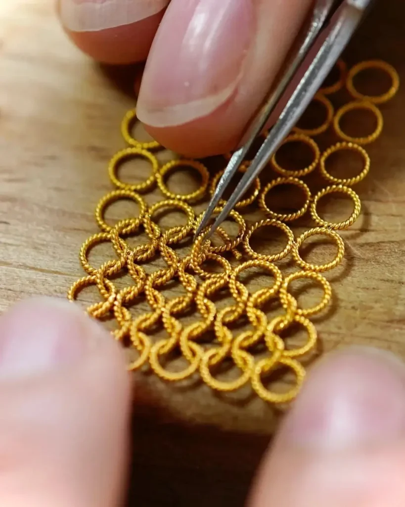Macro view of an artisan interlacing single gold wires into a delicate, mesh-like base.