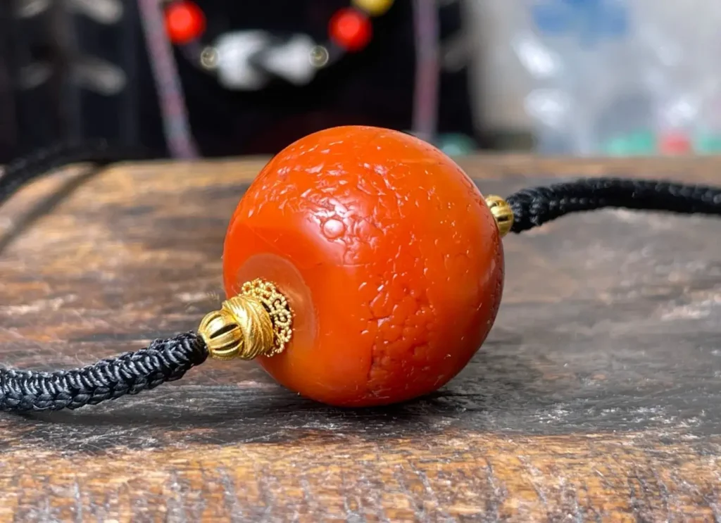 A 27mm Gannan red agate bead with perfect persimmon red color and natural surface weathering.