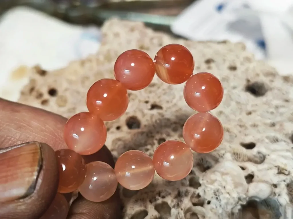 Close-up of African Agate beads showing watery luster and pale, purplish-red tones.