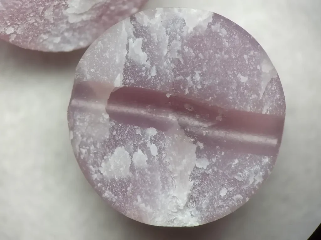Cross-section of a broken purple jade bead showing colorless wax in the drill hole and uniform core.