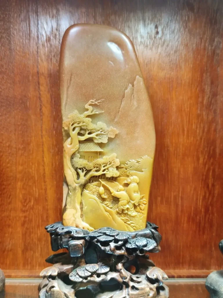 Intricately carved Taishan Jade ornament showcasing smooth waxy texture and warm golden-red hues.