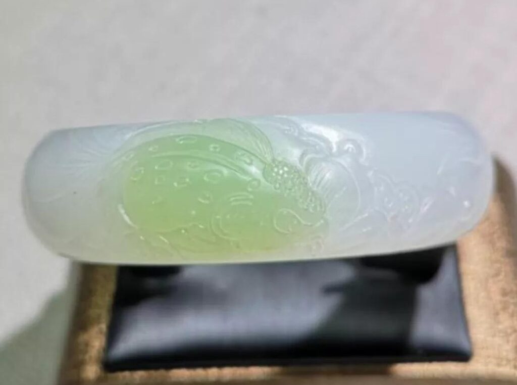 Composite nephrite bangle with a thin layer of green jade bonded onto a white base.