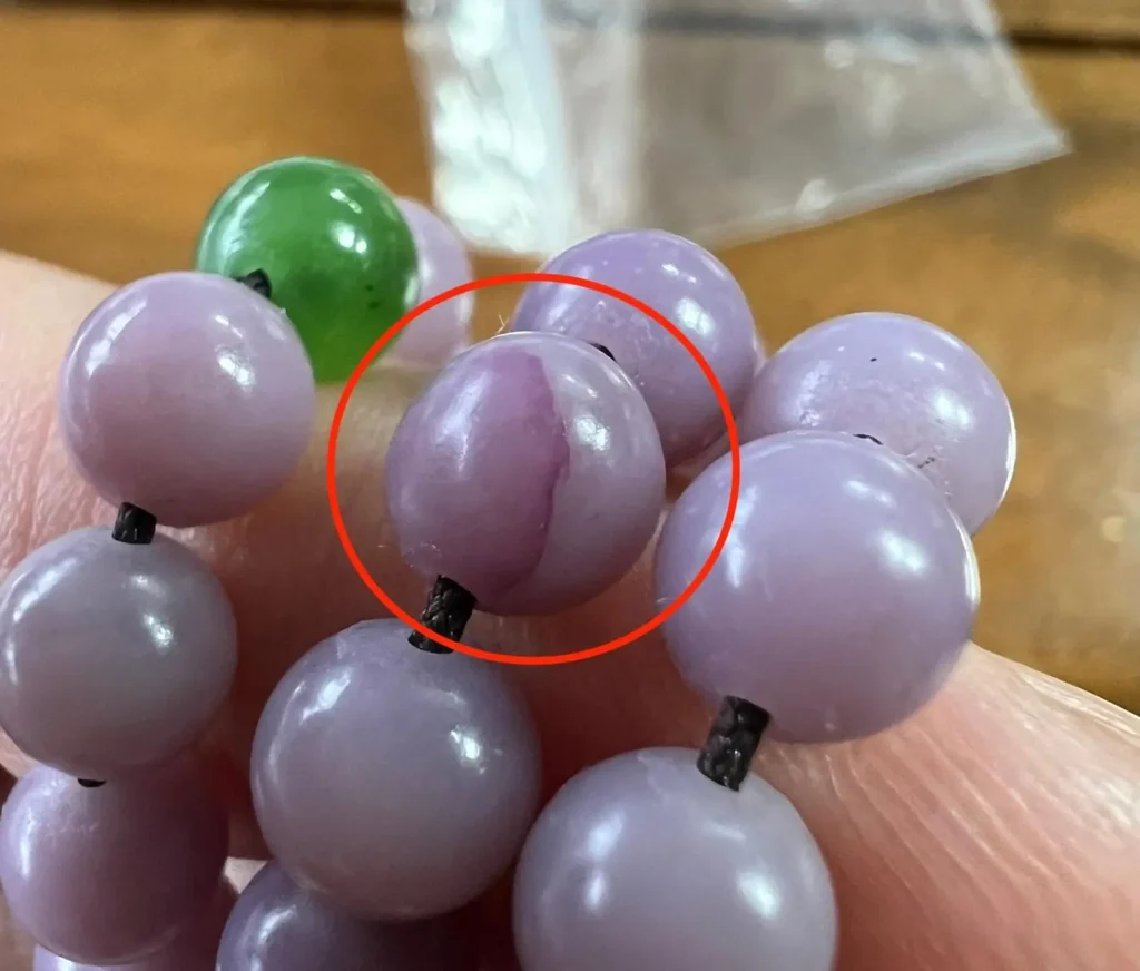 Close-up of a purple Hetian jade bead showing localized dye pooling on the surface.