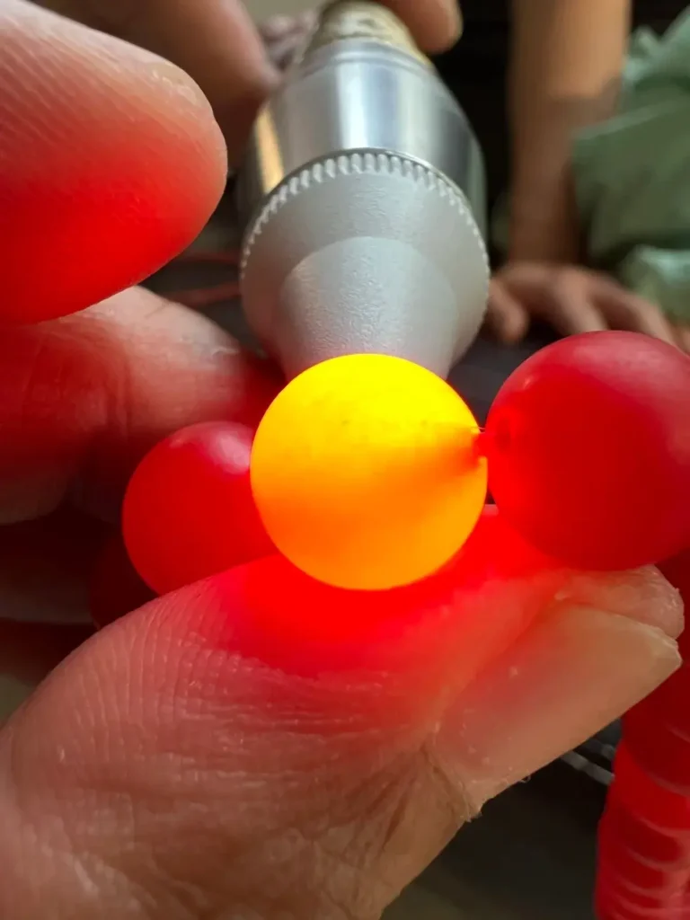 Backlit dyed quartzite bead showing internal stress fractures and lack of Nanhong agate banding.