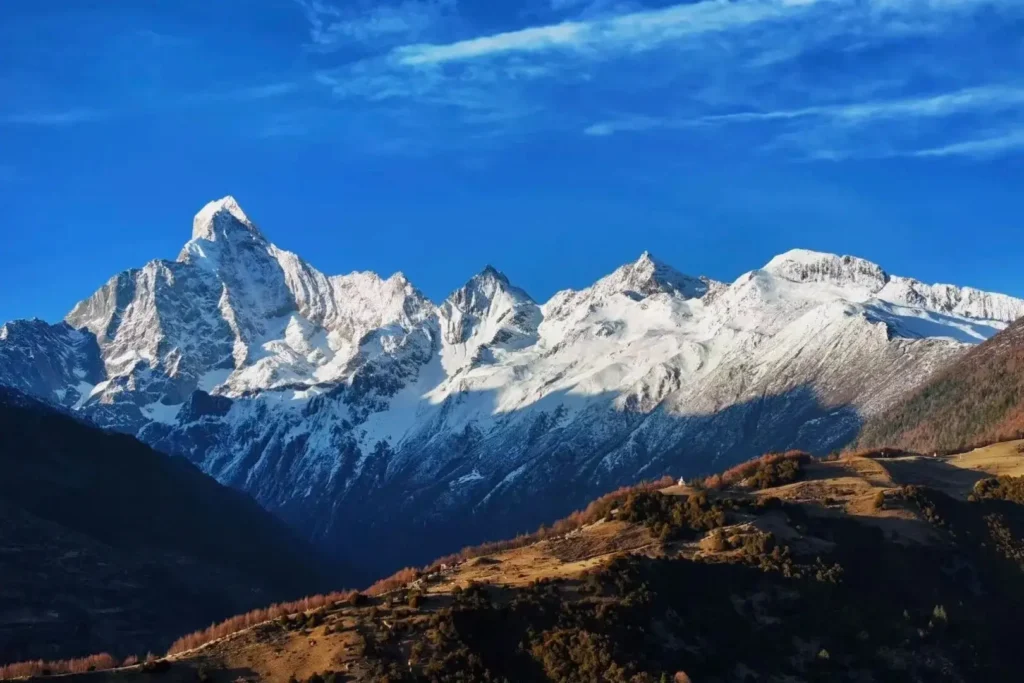 Four snow-capped peaks of Mount Siguniang in Sichuan under a clear sky.