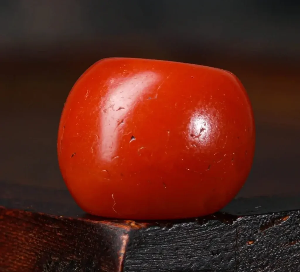A 13mm Gannan red agate barrel bead with full-bodied persimmon red color and fine weathered texture.