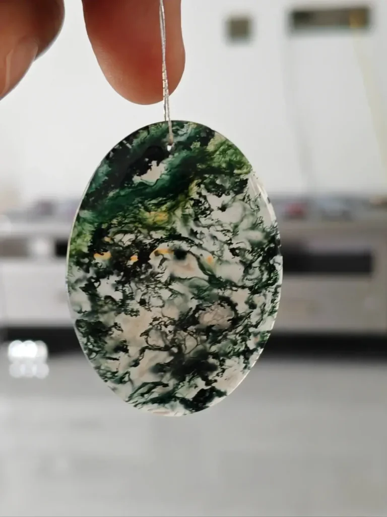 A green moss agate pendant showing natural plant-like mineral inclusions inside the stone.