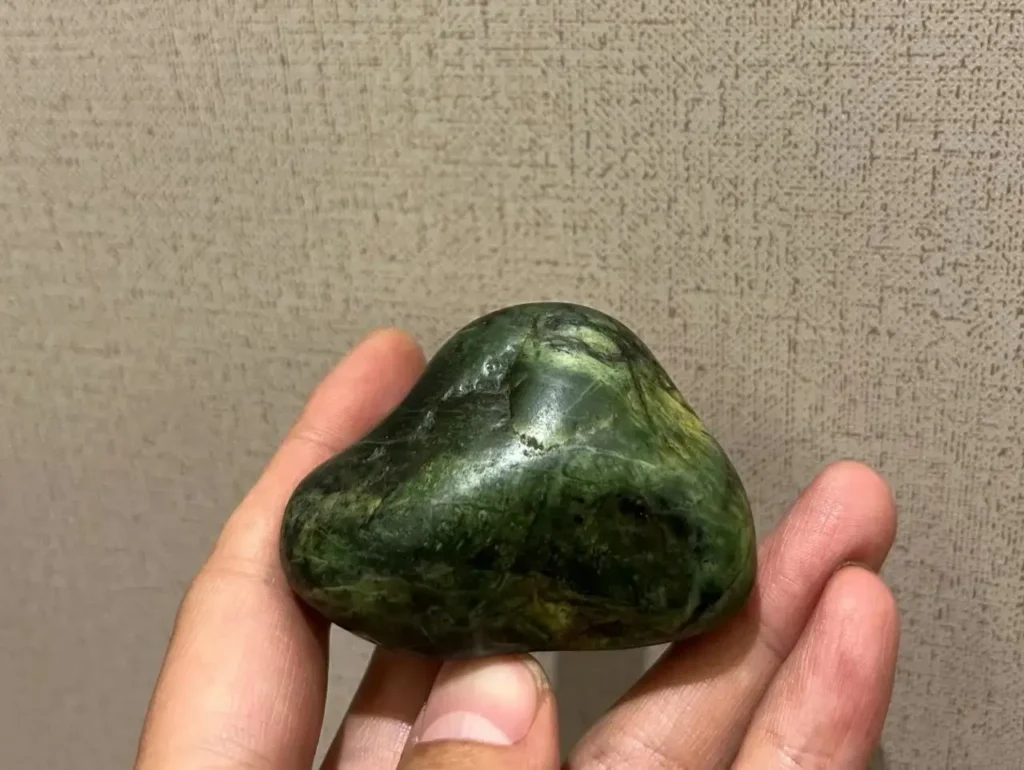 A person holding a piece of light green Renbu Stone sourced from Rinbung County, Tibet.