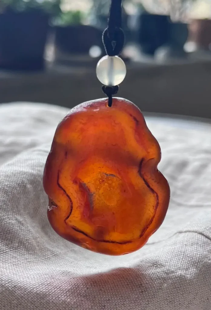 Natural Beihong agate raw stone pendant from Heilongjiang with translucent crimson and amber.
