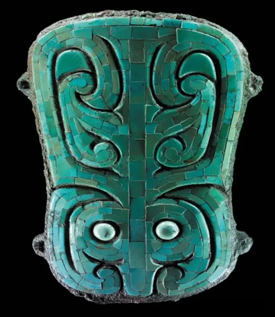 A Henan Erlitou bronze plaque inlaid with turquoise mosaics forming a stylized animal face.