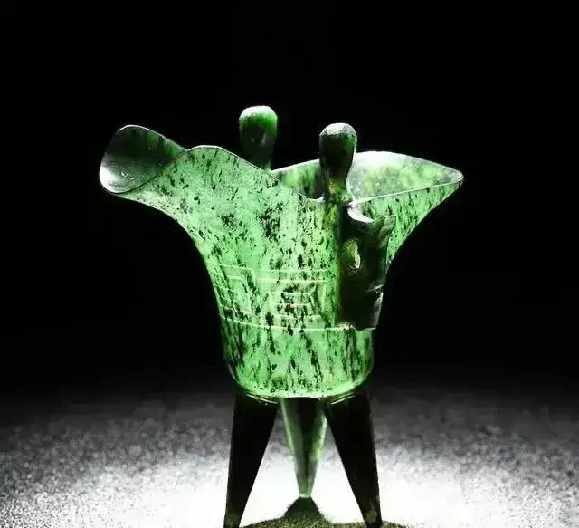 Dark green Jiuquan Jade luminous cup with characteristic black serpentine inclusions and oily luster.