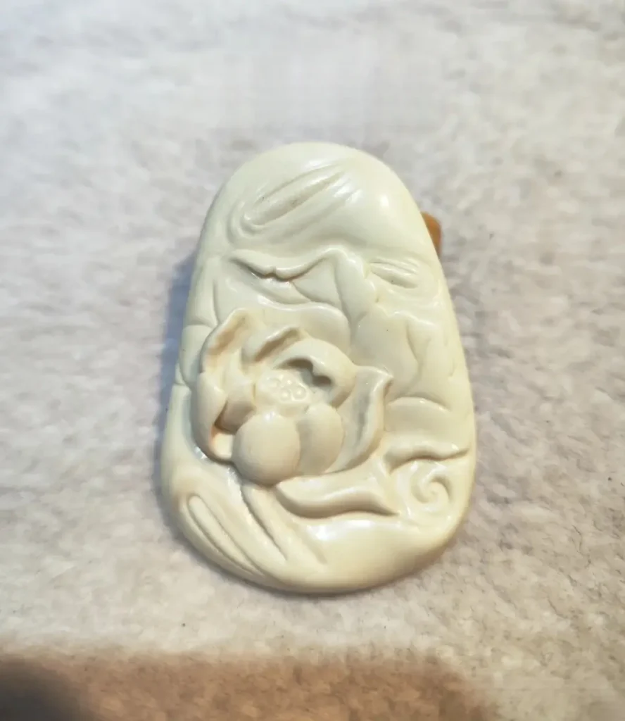 A porcelain white Ivory Magnesite pendant carved with a lotus and leaf design from Tibet.
