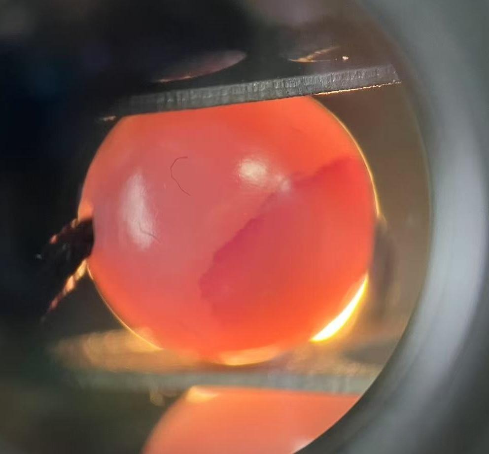 Microscopic view of a dyed bead showing heavy pigment sediment inside surface fissures.