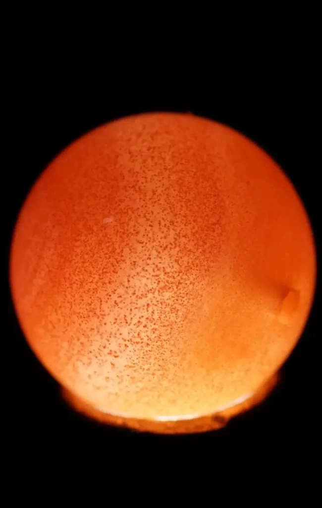 Microscopic cinnabar dots and hematite inclusions in natural Nanhong Agate under backlighting.